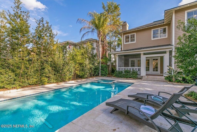 view of swimming pool with a patio, a sunroom, an in ground hot tub, and french doors