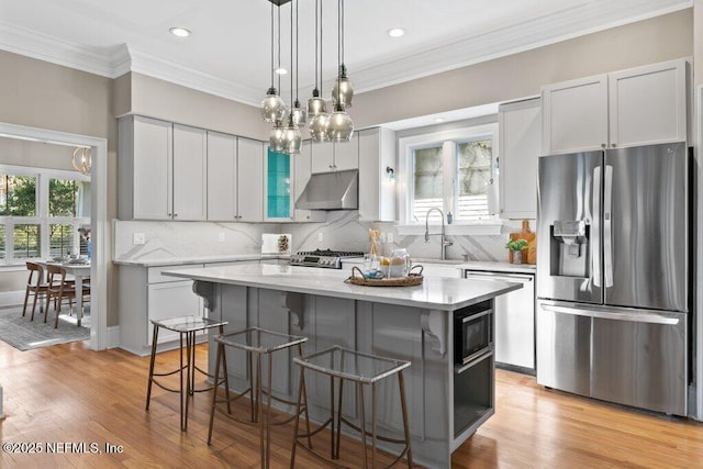 kitchen featuring a kitchen bar, sink, a center island, hanging light fixtures, and stainless steel fridge