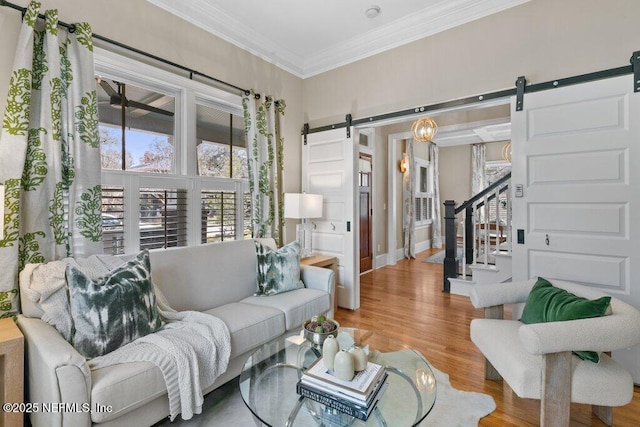 living room with ornamental molding, a barn door, and light wood-type flooring