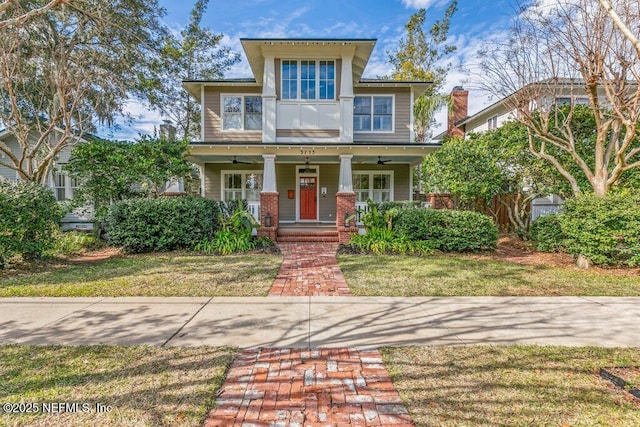 view of front of house with a front yard, ceiling fan, and covered porch