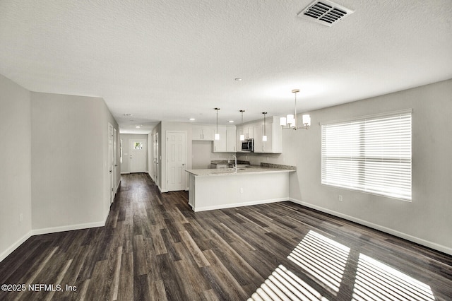 kitchen featuring sink, white cabinetry, dark hardwood / wood-style flooring, kitchen peninsula, and pendant lighting