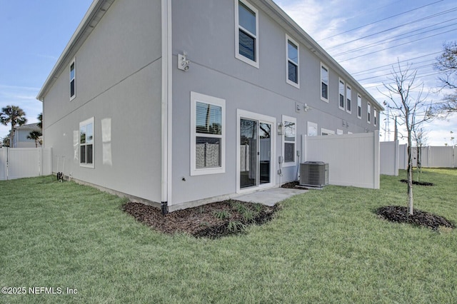 rear view of house with central AC and a lawn