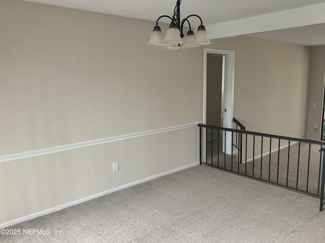 carpeted spare room featuring a chandelier