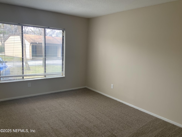 carpeted empty room featuring a textured ceiling