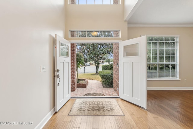 entrance foyer featuring light hardwood / wood-style flooring, ornamental molding, and a high ceiling