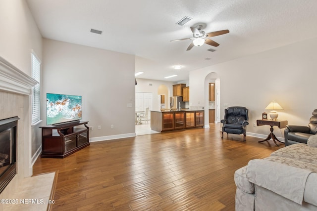 living room featuring hardwood / wood-style floors, a textured ceiling, a premium fireplace, and ceiling fan