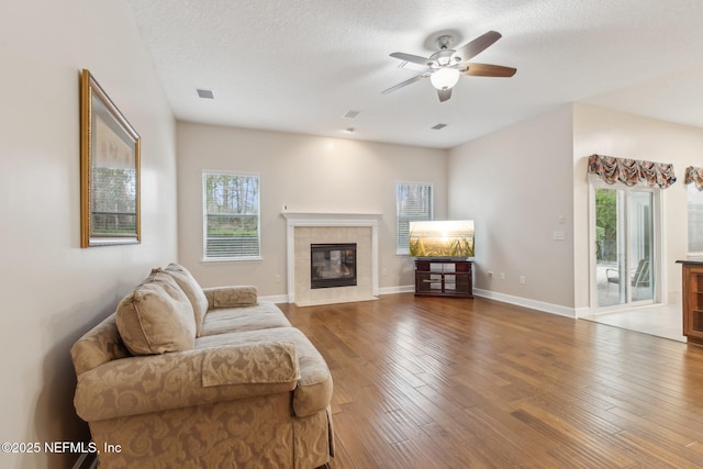 living room with ceiling fan, wood-type flooring, a fireplace, and a textured ceiling