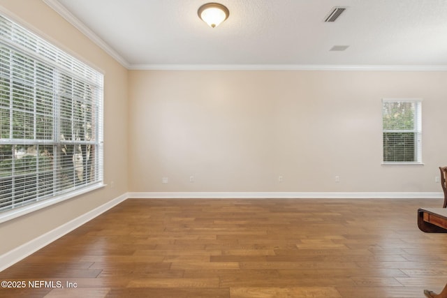 spare room featuring hardwood / wood-style floors, crown molding, and a healthy amount of sunlight