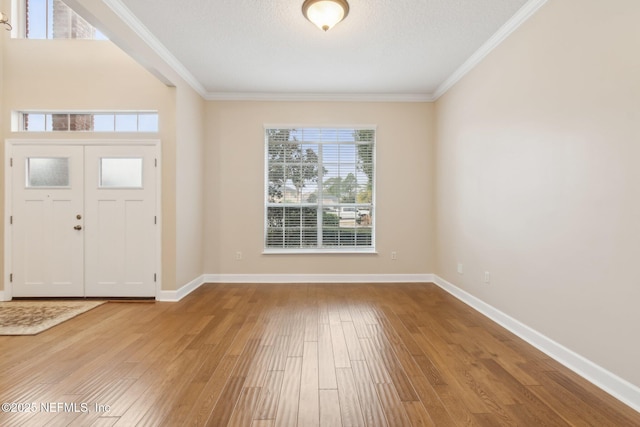 foyer entrance featuring ornamental molding, a textured ceiling, and light wood-type flooring