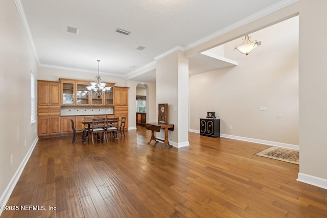 dining space featuring crown molding, dark wood-type flooring, and an inviting chandelier