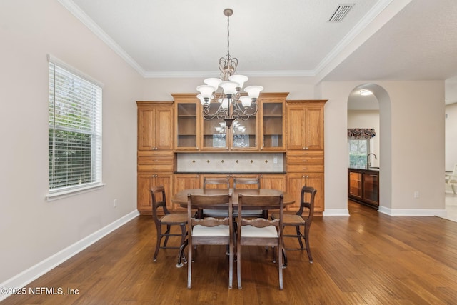 dining area featuring an inviting chandelier, dark wood-type flooring, and ornamental molding