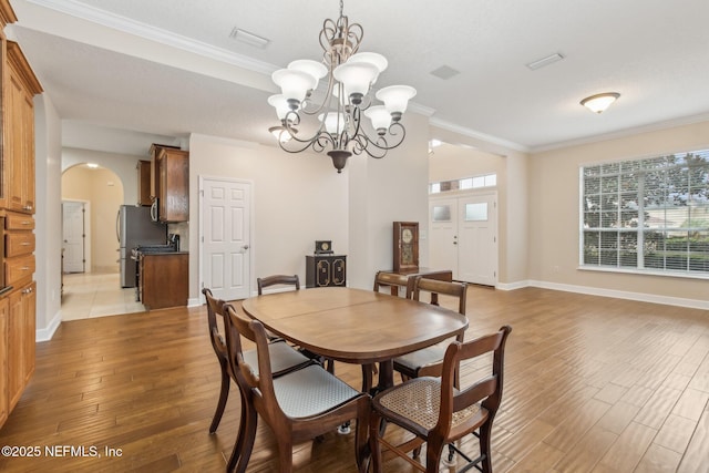 dining area featuring crown molding, a notable chandelier, and light wood-type flooring