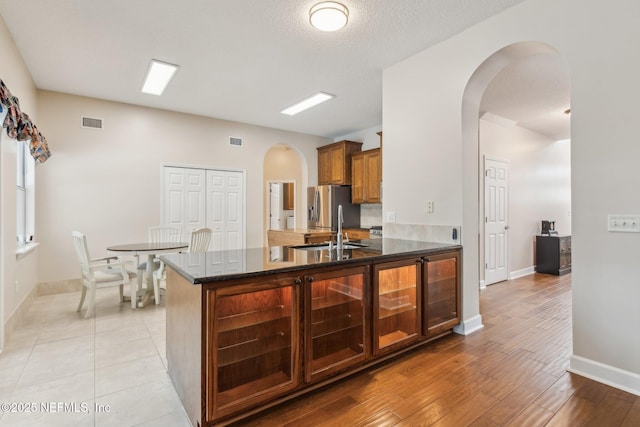 kitchen with light hardwood / wood-style flooring, sink, stainless steel fridge, and kitchen peninsula