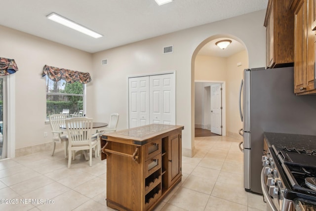 kitchen featuring light tile patterned flooring, tile countertops, gas stove, and a kitchen island