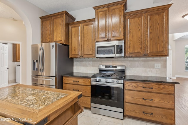 kitchen with tasteful backsplash, appliances with stainless steel finishes, and dark stone counters