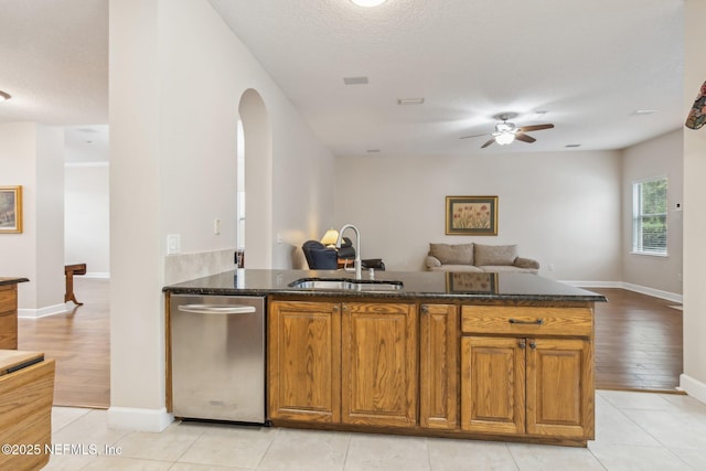 kitchen with dark stone counters, dishwasher, sink, and light tile patterned floors