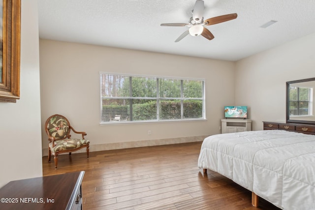 bedroom featuring hardwood / wood-style flooring, ceiling fan, multiple windows, and a textured ceiling