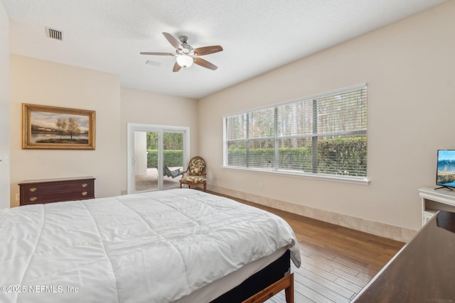 bedroom featuring ceiling fan, hardwood / wood-style floors, a textured ceiling, and access to outside