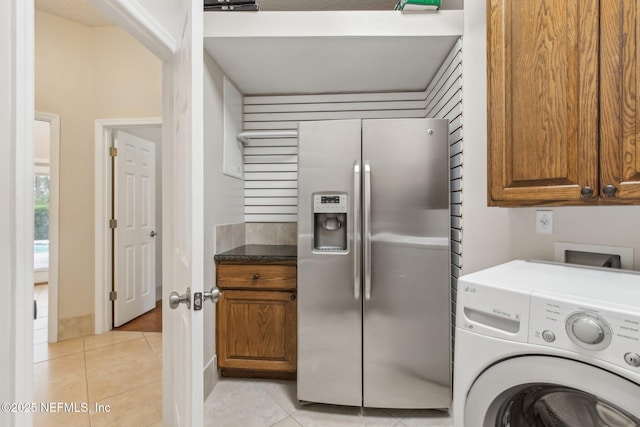 clothes washing area with cabinets, washer / dryer, and light tile patterned floors