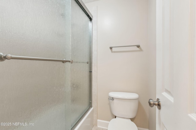 bathroom with bath / shower combo with glass door and toilet