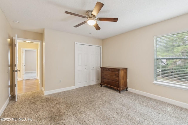 unfurnished bedroom featuring light colored carpet, a closet, multiple windows, and a textured ceiling