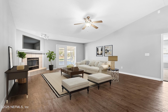 living room with ceiling fan, dark hardwood / wood-style floors, a fireplace, track lighting, and vaulted ceiling