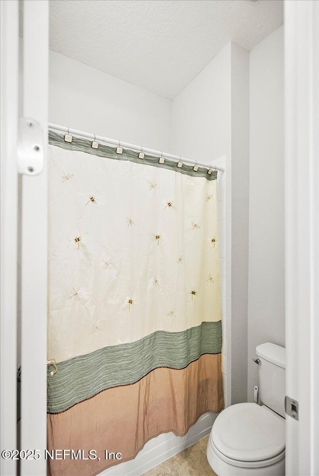 bathroom featuring shower / tub combo with curtain, a textured ceiling, and toilet