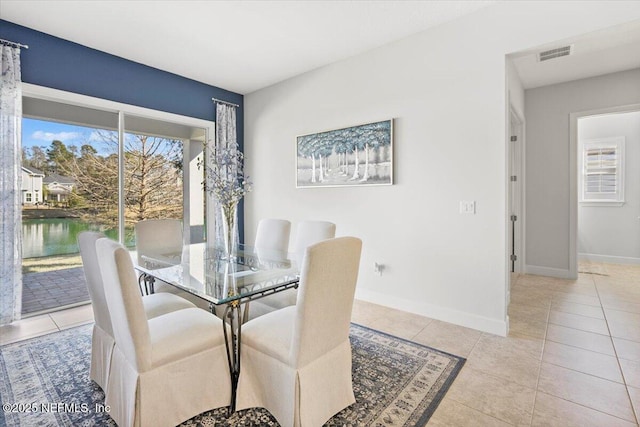 dining area with a water view and light tile patterned floors