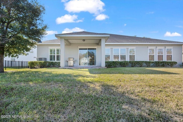 rear view of property featuring central AC unit and a lawn