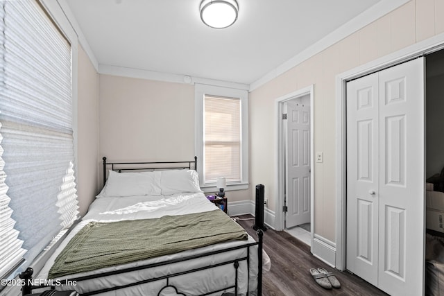 bedroom featuring dark wood-type flooring, crown molding, and a closet