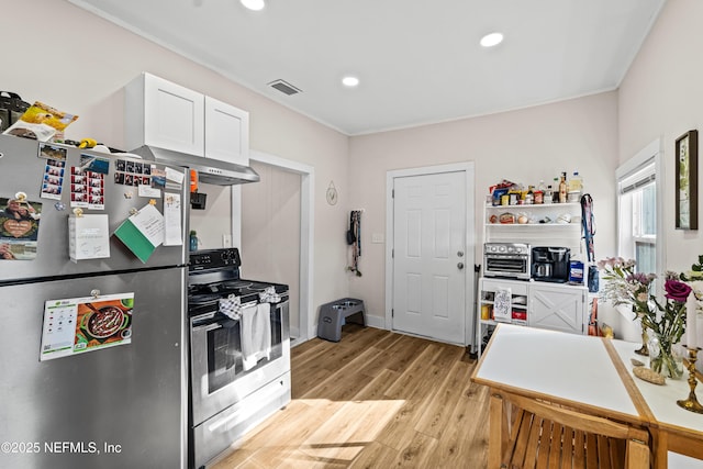 kitchen featuring white cabinetry, ornamental molding, stainless steel appliances, wall chimney range hood, and light hardwood / wood-style flooring