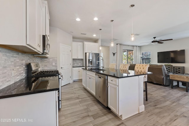 kitchen featuring a kitchen island with sink, sink, white cabinetry, and appliances with stainless steel finishes