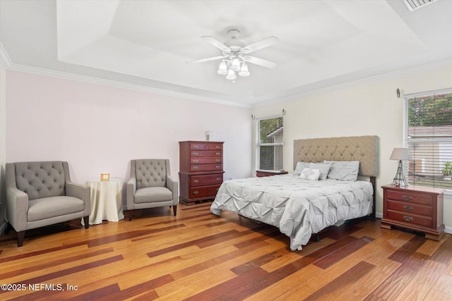 bedroom featuring wood finished floors, multiple windows, and a raised ceiling