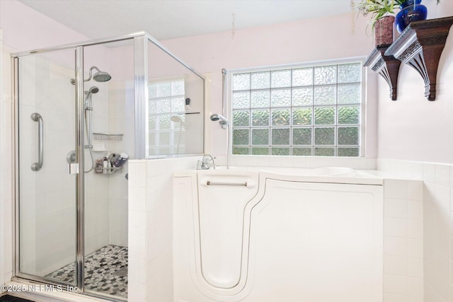 bathroom with a stall shower and a garden tub