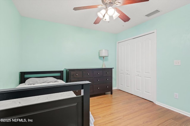 bedroom with light wood-type flooring, baseboards, visible vents, and a closet