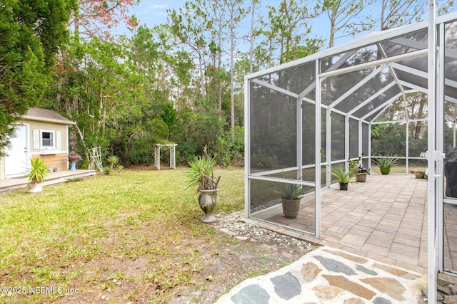 view of yard featuring a lanai, a patio area, a storage unit, and an outbuilding