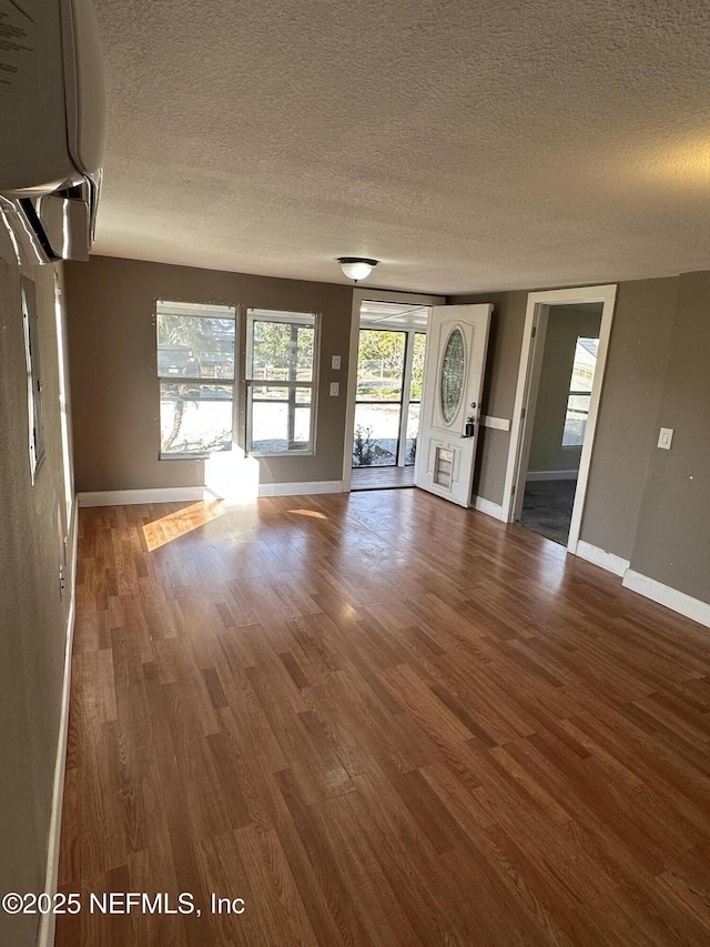 unfurnished living room featuring dark hardwood / wood-style flooring and a textured ceiling