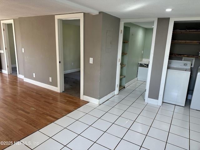 interior space with light tile patterned floors, washer and dryer, and a textured ceiling