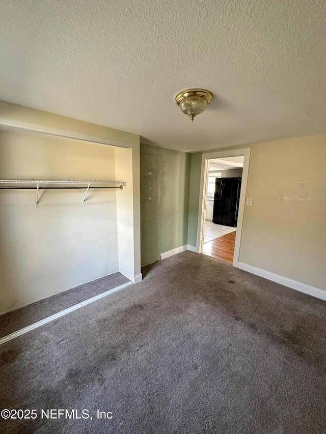 unfurnished bedroom featuring carpet flooring, a textured ceiling, and a closet