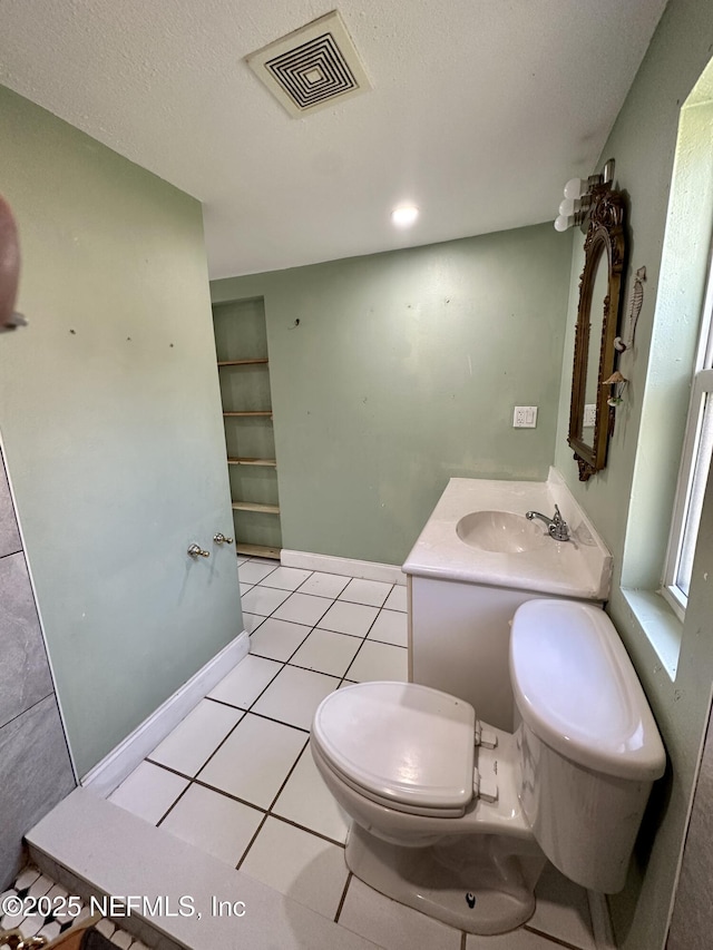 bathroom with vanity, toilet, tile patterned flooring, and a textured ceiling