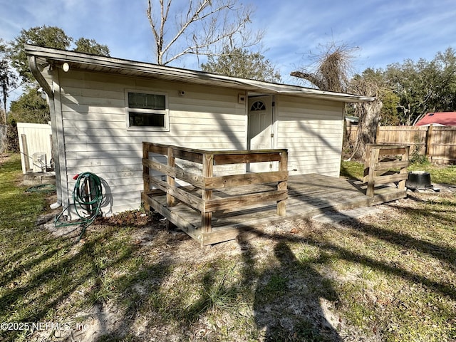 rear view of property with a wooden deck and a yard