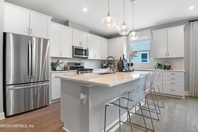 kitchen with sink, a center island with sink, appliances with stainless steel finishes, light hardwood / wood-style floors, and white cabinets