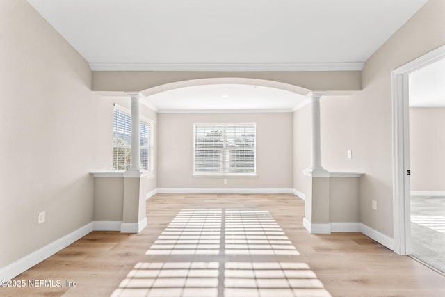 hallway featuring ornate columns, ornamental molding, and light hardwood / wood-style floors