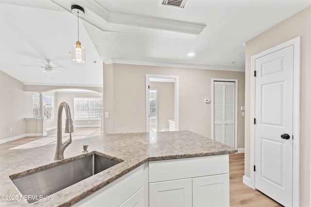 kitchen with sink, crown molding, white cabinetry, hanging light fixtures, and light hardwood / wood-style floors