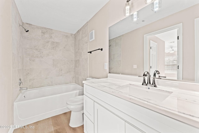 full bathroom with hardwood / wood-style flooring, vanity, toilet, and tiled shower / bath combo