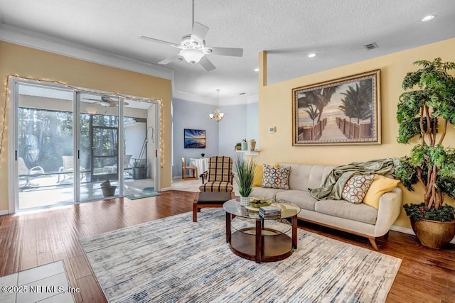 living room featuring hardwood / wood-style flooring, crown molding, ceiling fan with notable chandelier, and a textured ceiling