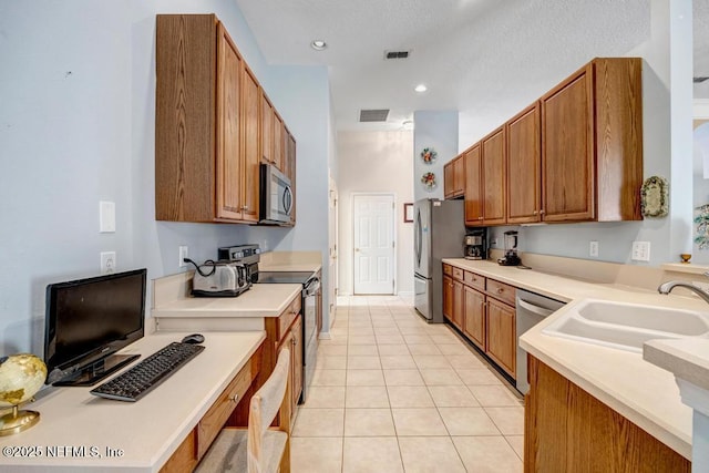 kitchen with appliances with stainless steel finishes, sink, and light tile patterned floors