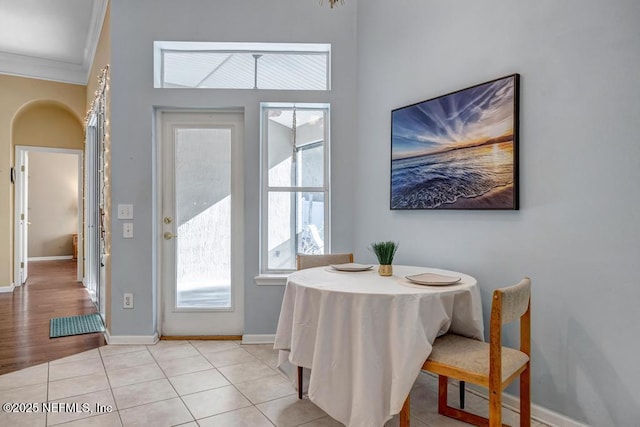 tiled dining room featuring crown molding and a healthy amount of sunlight