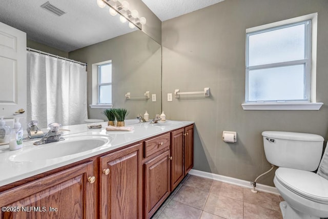 bathroom featuring tile patterned flooring, vanity, a textured ceiling, and toilet