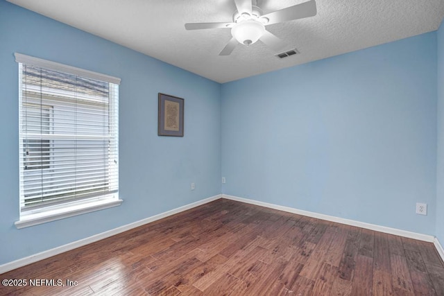 spare room featuring dark wood-type flooring, ceiling fan, a healthy amount of sunlight, and a textured ceiling